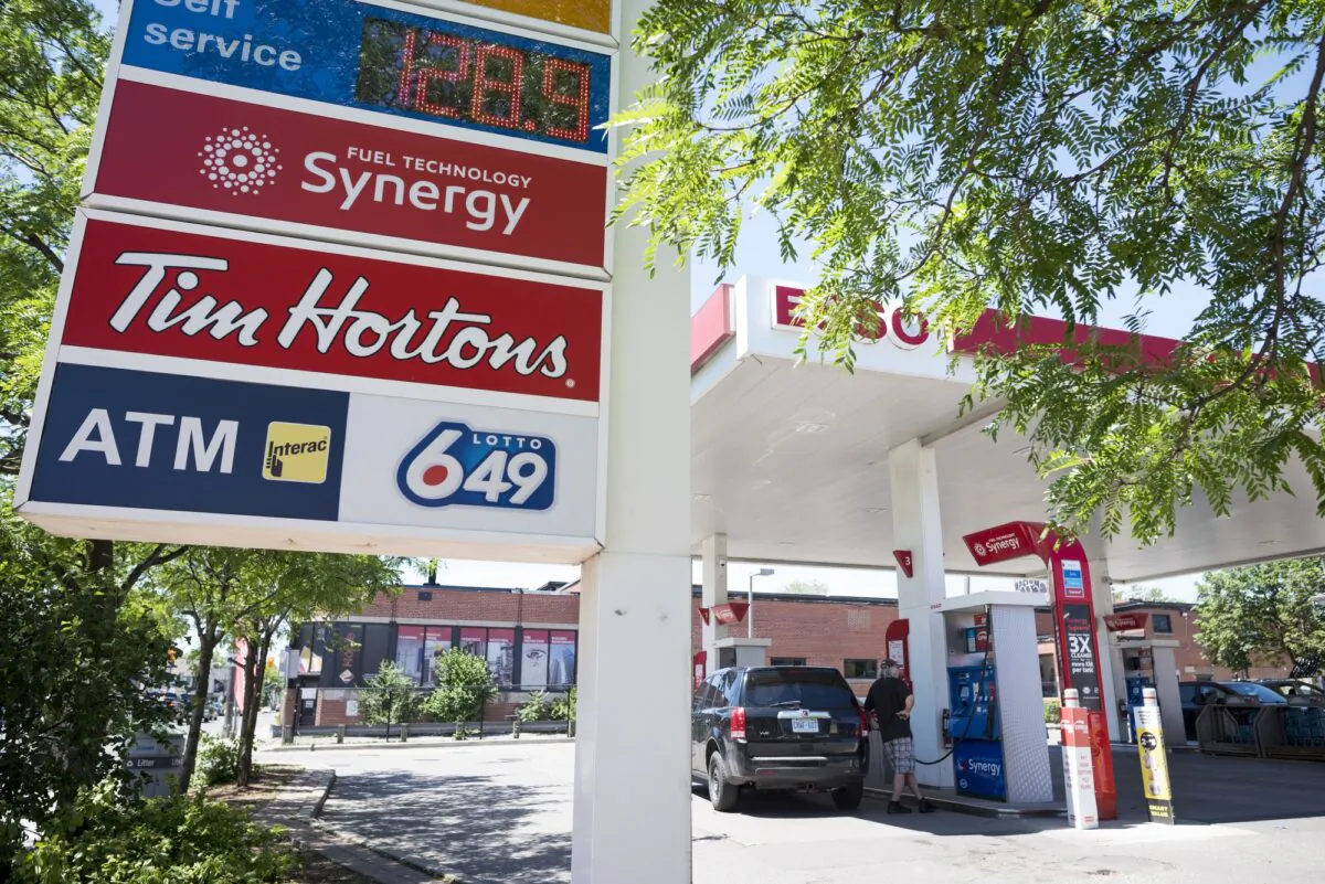 A commuter pumps gas at an Esso gas station in Toronto on June 15, 2021. As the price of oil rises, the cost of many goods in the economy are also going up. (The Canadian Press/Tijana Martin)