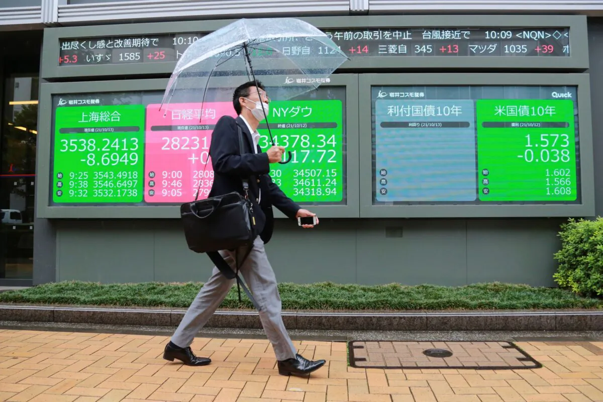 A man walks by an electronic stock board of a securities firm in Tokyo, Japan on Oct. 13, 2021. (Koji Sasahara/AP Photo)