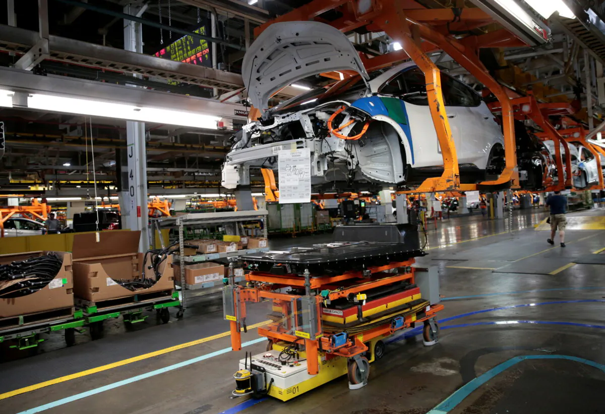 An automated guided vehicle carrying a battery pack moves under a partially assembled 2018 Chevrolet Bolt EV vehicle on the assembly line at General Motors Orion Assembly in Lake Orion, Mich., on March 19, 2018. (Rebecca Cook/Reuters)