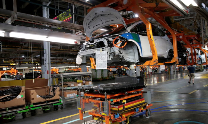 An automated guided vehicle carrying a battery pack moves under a partially assembled 2018 Chevrolet Bolt EV vehicle on the assembly line at General Motors Orion Assembly in Lake Orion, Mich., on March 19, 2018. (Rebecca Cook/Reuters)