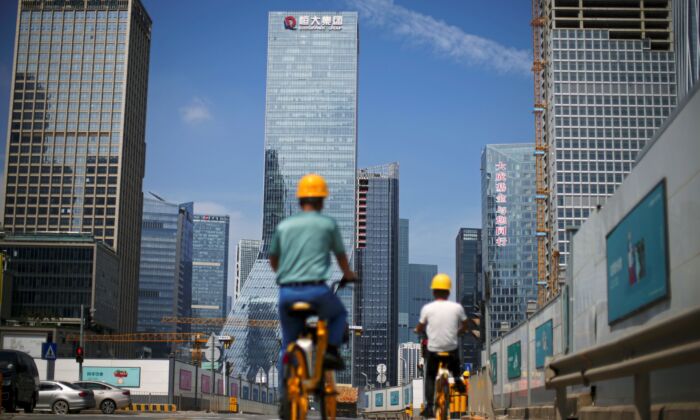 Men ride bicycles past construction sites near the headquarters of China's Evergrande Group in Shenzhen, Guangdong Province, China on Sept. 26, 2021. (Aly Song/Reuters)