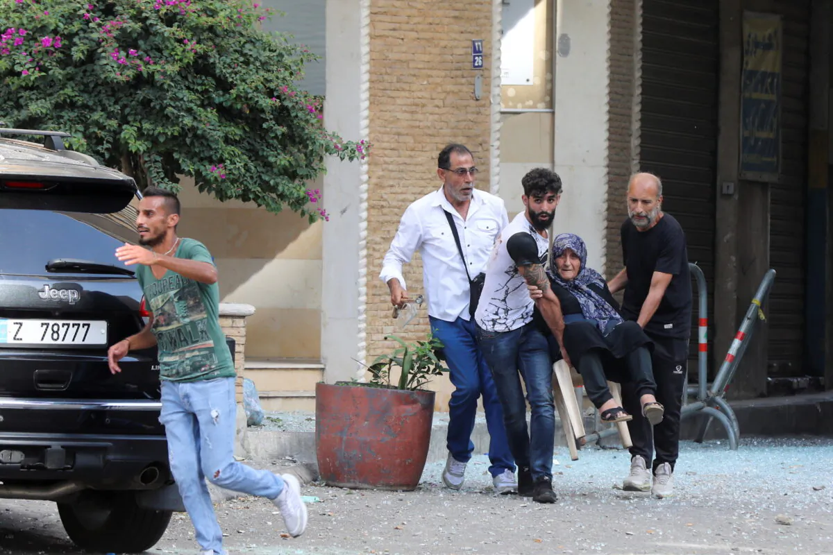 Men help evacuate an elderly woman after gunfire erupted, in Beirut, Lebanon, on Oct. 14, 2021. (Mohamed Azakir/Reuters)