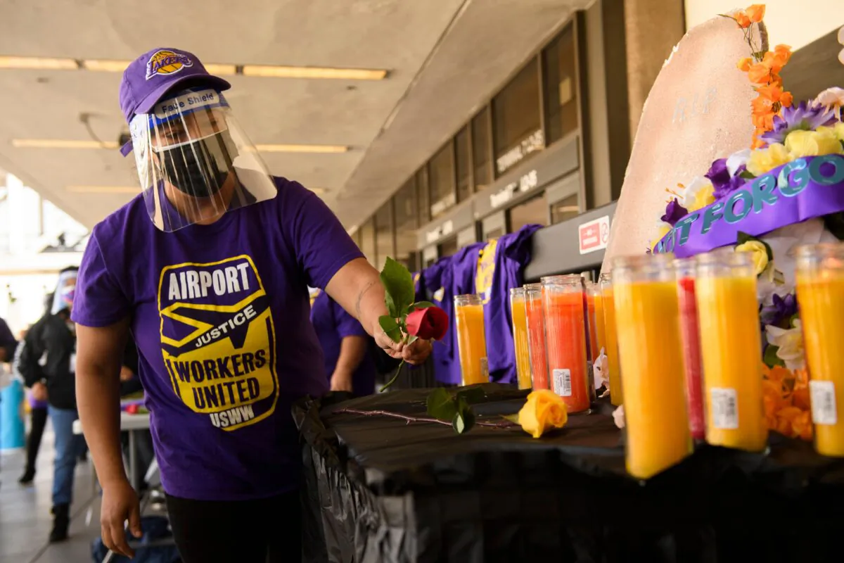 An airport worker in support of the Service Employees International Union (SEIU) leaves a flower at an altar as they protest and call on California Gov. Gavin Newsom to support vaccine priority for essential workers during the COVID-19 pandemic at Los Angeles International Airport (LAX) on Feb. 4, 2021. (Patrick T. Fallon/AFP via Getty Images)