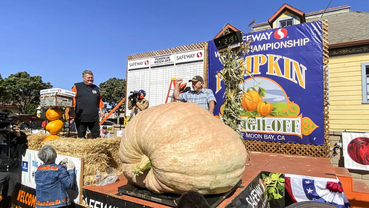 Jeff Uhlmeyer stands behind his 2,191-pound pumpkin, which won the 48th Safeway World Championship Pumpkin Weigh-Off at I.D.E.S. Portuguese Hall in Half Moon Bay on Oct. 11, 2021. (Ilene Eng/The Epoch Times)