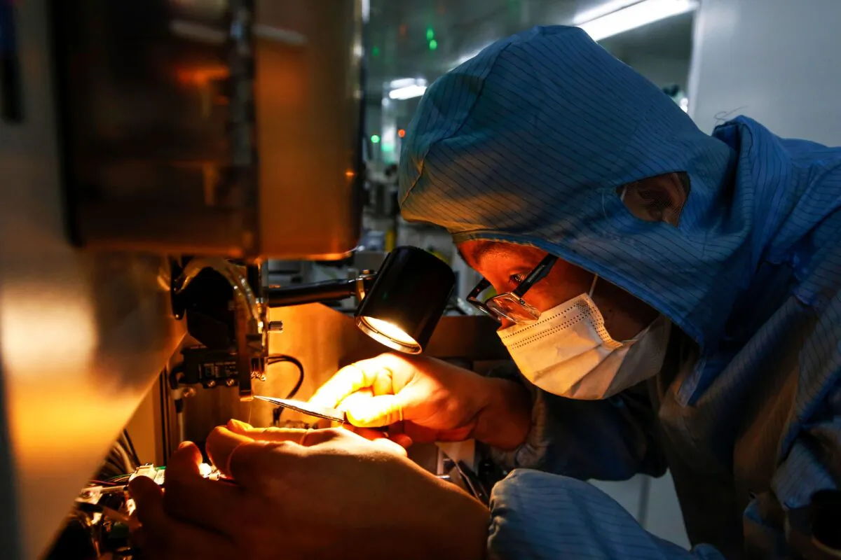 A Chinese employee wearing a mask and protective suit works on a smart chip production line in Sihong county in China's eastern Jiangsu Province on Feb. 16, 2020. (STR/AFP) 