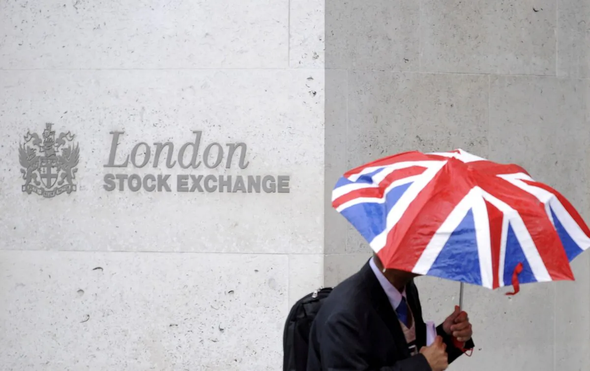 A worker shelters from the rain under a Union Flag umbrella as he passes the London Stock Exchange in London, Britain, on Oct. 1, 2008. (Toby Melville/Reuters)