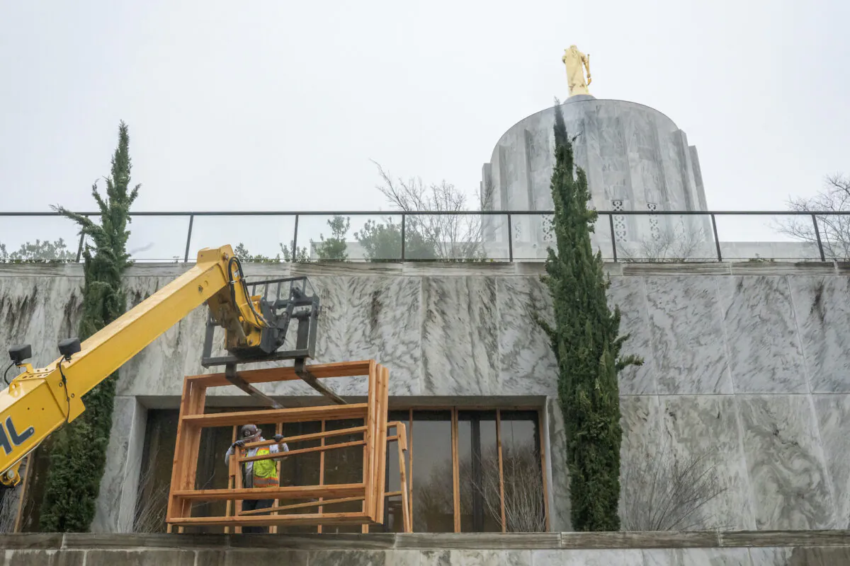 Workers cover ground floor windows with plywood at the state Capitol building in Salem, Ore., on Jan. 15, 2021. (Nathan Howard/Getty Images)