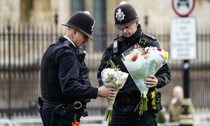 Following the murder of Conservative MP Sir David Amess, Police move flowers left in Parliament Square in London on Oct. 16, 2021. (Aaron Chown/PA)