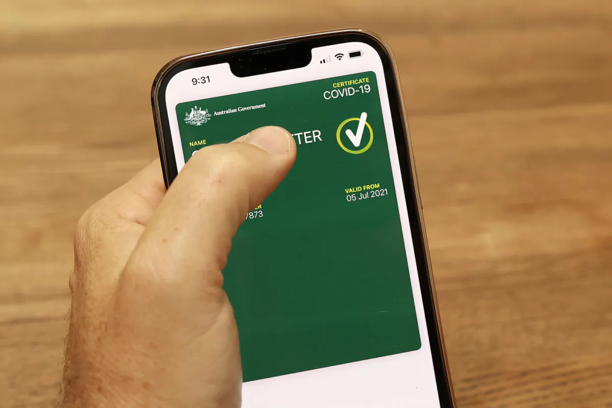 In this photo illustration a man holds a phone displaying a valid Australian digital COVID-19 vaccine certificate in Sydney, Australia, on Oct. 14, 2021. (Cameron Spencer/Getty Images)