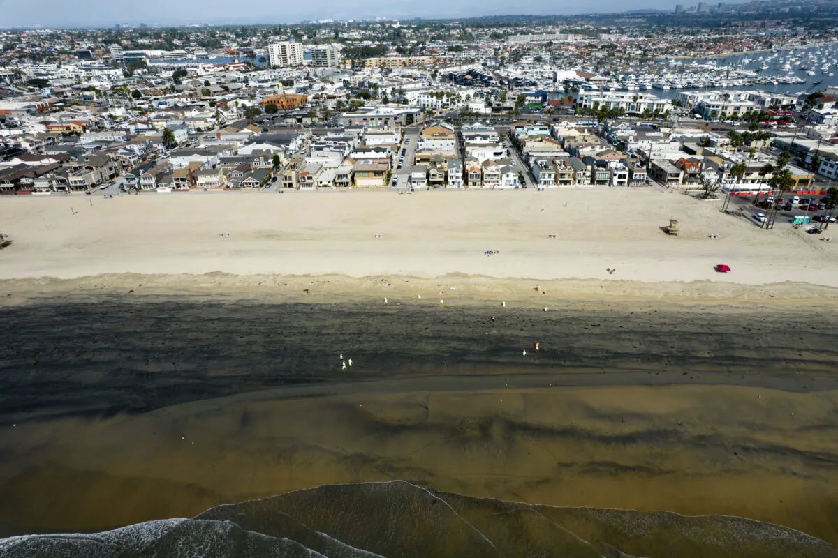 In this aerial image taken with a drone, workers in protective suits clean the contaminated beach after an oil spill in Newport Beach, Calif., on Oct. 6, 2021. (Ringo H.W. Chiu/AP Photo)