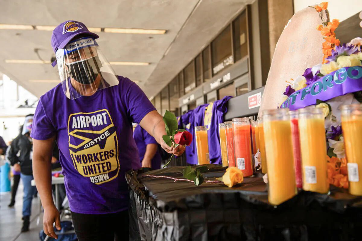 An airport worker in support of the Service Employees International Union (SEIU) leaves a flower at an altar as they protest and call on California Governor Gavin Newsom to support vaccine priority for essential workers during the Covid-19 pandemic at Los Angeles International Airport (LAX) in Los Angeles, California, on Feb. 4, 2021. (Patrick T. Fallon/AFP via Getty Images)