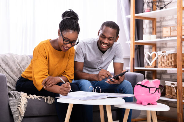 Young,African,Couple,Sitting,On,Sofa,Calculating,Invoice