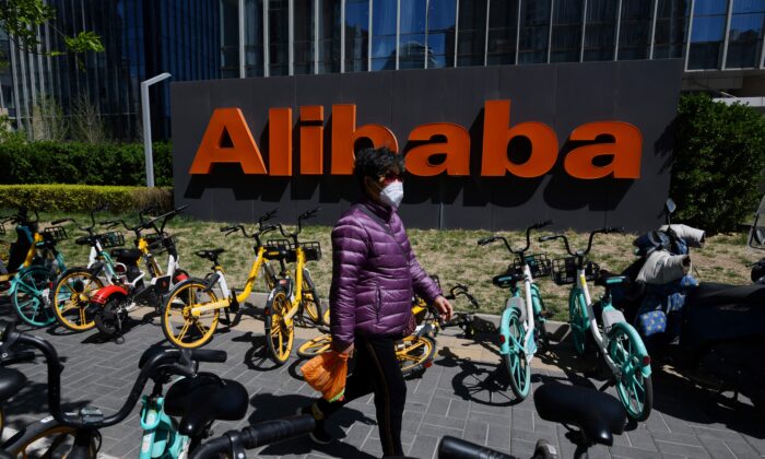 A woman walks past an Alibaba sign outside the company's office in Beijing, China, on April 13, 2021. (Greg Baker/AFP via Getty Images)