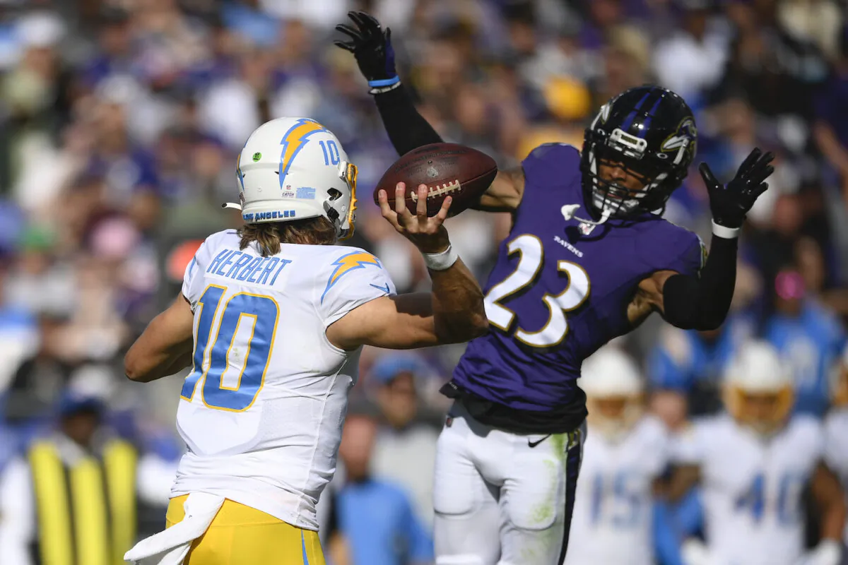 Baltimore Ravens cornerback Anthony Averett (23) applies pressure on Los Angeles Chargers quarterback Justin Herbert (10) during the second half of an NFL football game in Baltimore on Oct. 17, 2021. (AP Photo/Nick Wass)
