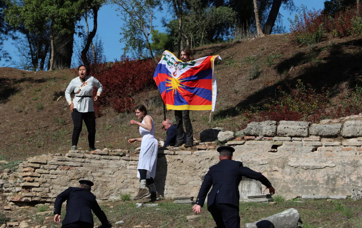 A protester holds a Tibetan flag during the Olympic flame lighting ceremony for the Beijing 2022 Winter Olympics in Ancient Olympia, Greece, on Oct. 18, 2021. (Costas Baltas/Reuters)