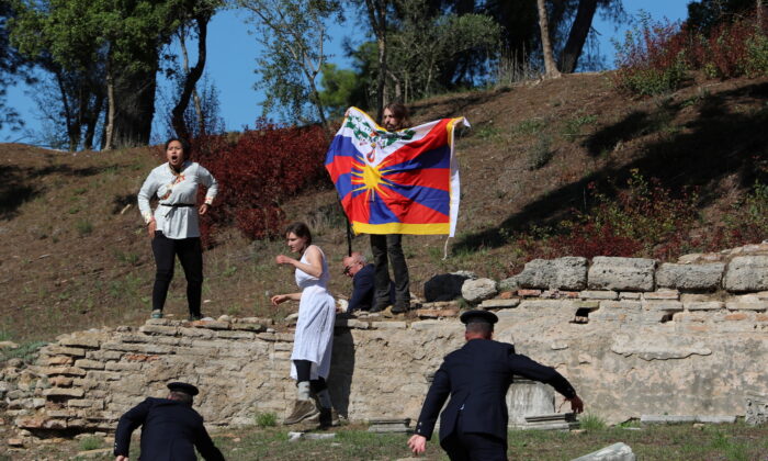 A protester holds a Tibetan flag during the Olympic flame lighting ceremony for the Beijing 2022 Winter Olympics in Ancient Olympia, Greece, on Oct. 18, 2021. (Costas Baltas/Reuters)