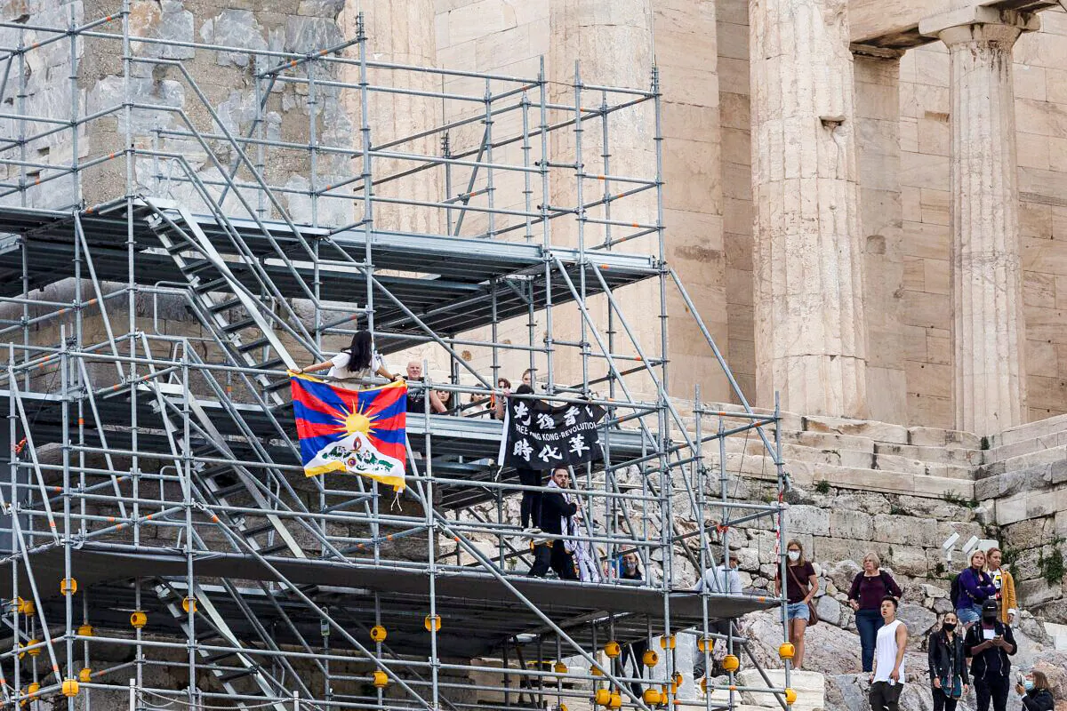Protesters raise a Tibetan flag and a banner from scaffolding at the Acropolis hill, in Athens, Greece, on Oct. 17, 2021. (Yorgos Karahalis/AP Photo)