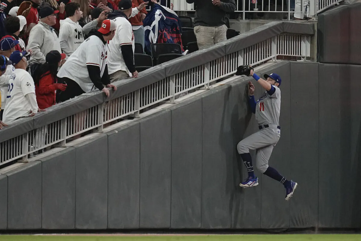 Los Angeles Dodgers left fielder AJ Pollock tries to catch a foul ball by Atlanta Braves' Terrance Gore during gate fifth inning in Game 2 of baseball’s National League Championship Series in Atlanta Oct. 17, 2021. (AP Photo/Ashley Landis)