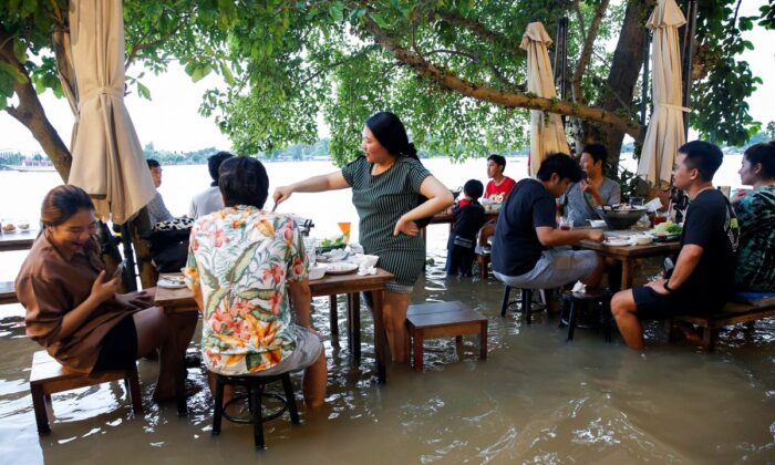 People eat food at a flooded restaurant on a river bank in Nonthaburi near Bangkok, Thailand, on Oct. 7, 2021. (Soe Zeya Tun/Reuters)