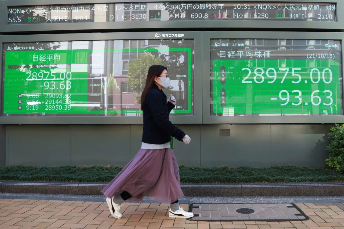 A woman walks by an electronic stock board of a securities firm in Tokyo, Japan on Oct. 18, 2021. (Koji Sasahara/AP Photo)