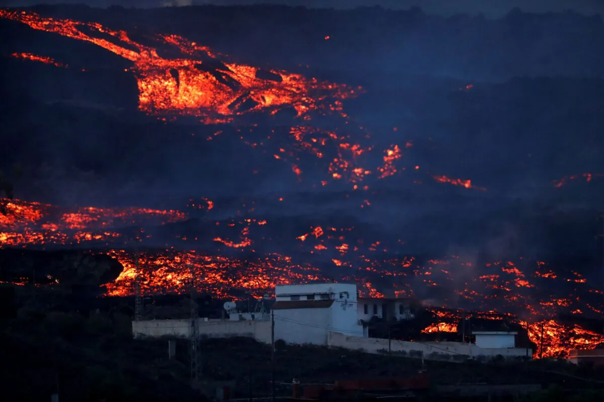 Lava from the Cumbre Vieja volcano flows among houses on the Canary Island of La Palma, as seen from Tajuya, Spain, on Oct. 19, 2021. (Susana Vera/Reuters)