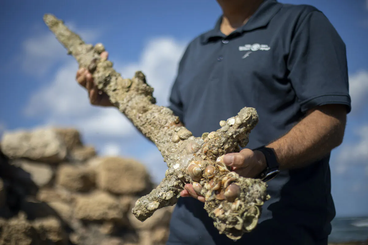 Jacob Sharvit, director of the Marine Archaeology Unit of the Israel Antiquities Authority, holds a yard-long sword, that experts say dates back to the Crusaders, in the Mediterranean seaport of Cesarea, Israel, on Oct. 19, 2021. (Ariel Schalit/AP Photo)