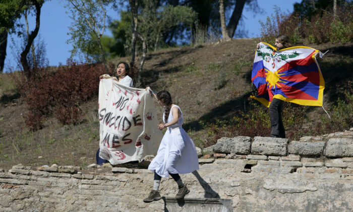 Protesters displaying a Tibetan flag and a banner reading "No genocide games" enter the grounds during the lighting of the Olympic flame at Ancient Olympia site, birthplace of the ancient Olympics, in southwestern Greece, on Oct. 18, 2021. (Thanassis Stavrakis/AP Photo)