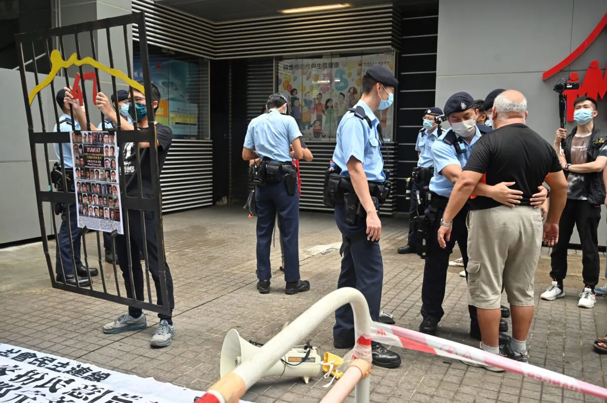A protester (right) is searched by police as Hong Kong began selecting a powerful committee under a new "patriots only" system imposed by Beijing, in Hong Kong, on Sept. 19, 2021. (Peter Parks/AFP via Getty Images)