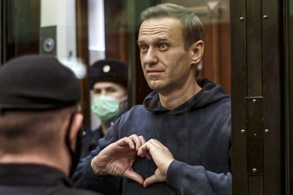 Russian opposition leader Alexei Navalny shows the heart symbol from the cage, during a hearing at the City Court in Moscow, Russia, on Feb. 2, 2021. (Moscow City Court via AP)