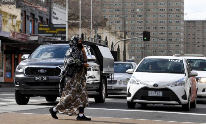 A woman crosses a road in front of a public housing high-rise in Melbourne, Australia, on Aug. 23, 2021. (William West/AFP via Getty Images)
