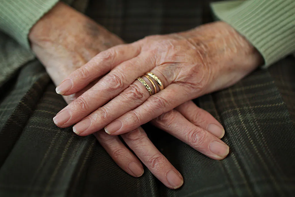 An elderly woman sits at home with her hands on her lap in Surrey, England, on Feb. 17, 2010. (Peter Macdiarmid/Getty Images)