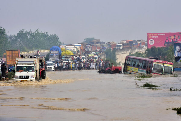 Commuters stand on a flyover on a flooded national highway after river Kosi overflowed following heavy rains near Rampur in India’s Uttar Pradesh state on Oct. 20, 2021. (AFP via Getty Images)