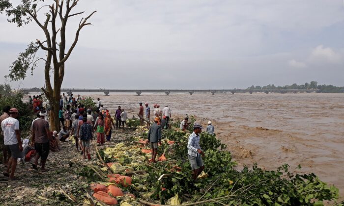 People stand along the banks of flooded Karnali river following heavy rains in Rajapur village of Bardiya district in Nepal on Oct. 20, 2021. (Krishna Adhikari/AFP via Getty Images)