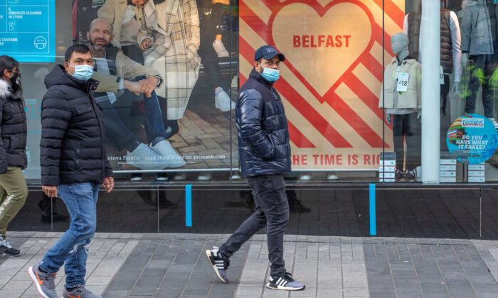 Pedestrians wearing a mask or covering due to the CCP virus pandemic, walk past a clothes shop in Belfast on Nov. 27, 2020. (Paul Faith/AFP via Getty Images)