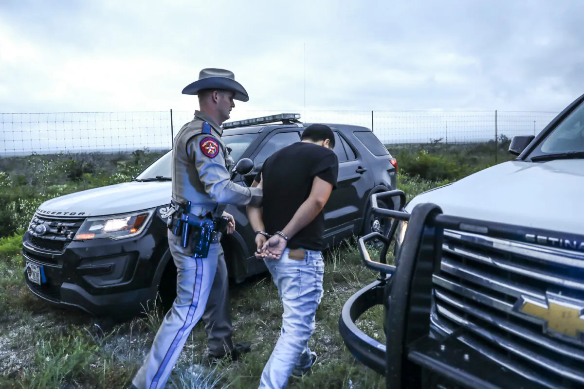 A Texas state trooper arrests a U.S. citizen who was transporting three illegal aliens to San Antonio, in Kinney County, Texas, on Oct. 20, 2021. (Charlotte Cuthbertson/The Epoch Times)