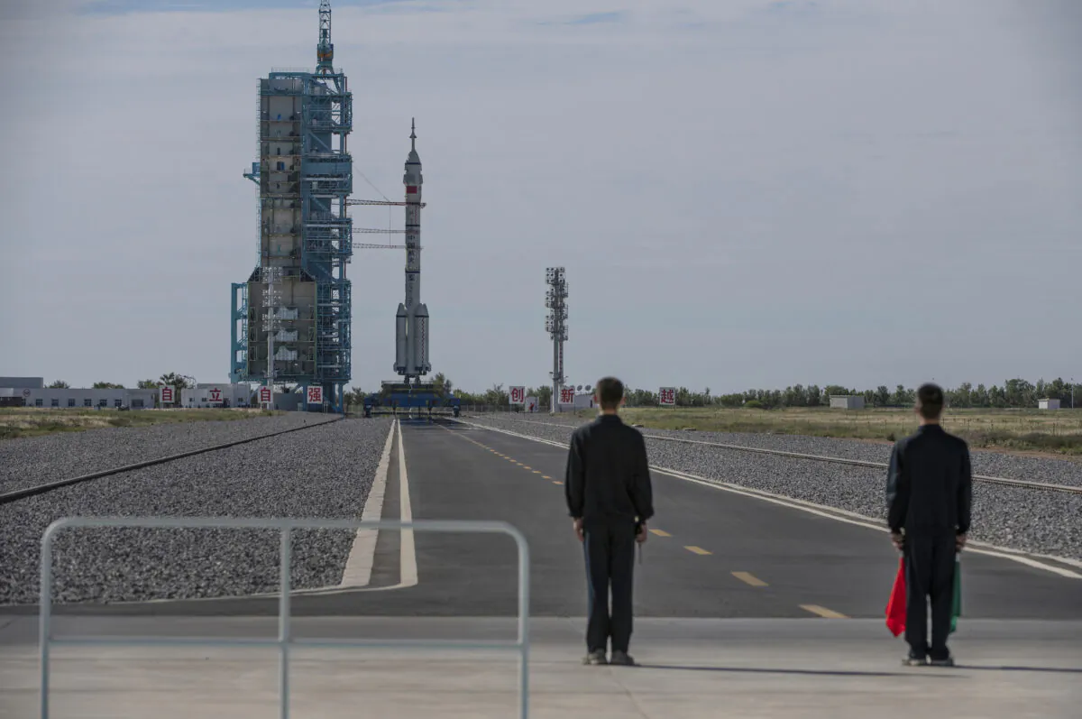 Workers stand near the manned Shenzhou-12 spacecraft from China's Manned Space Agency onboard the Long March-2F rocket before launch with three Chinese astronauts onboard at the Jiuquan Satellite Launch Center on June 17, 2021 in Jiuquan, Gansu province, China. (Kevin Frayer/Getty Images)