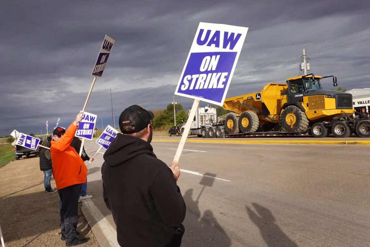 At truck hauls a piece of John Deere equipment from the factory past workers picketing outside of the John Deere Davenport Works facility in Davenport, Iowa, on Oct. 15, 2021. (Scott Olson/Getty Images)