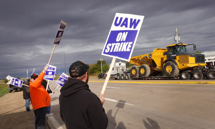At truck hauls a piece of John Deere equipment from the factory past workers picketing outside of the John Deere Davenport Works facility in Davenport, Iowa, on Oc. 15, 2021. (Scott Olson/Getty Images)