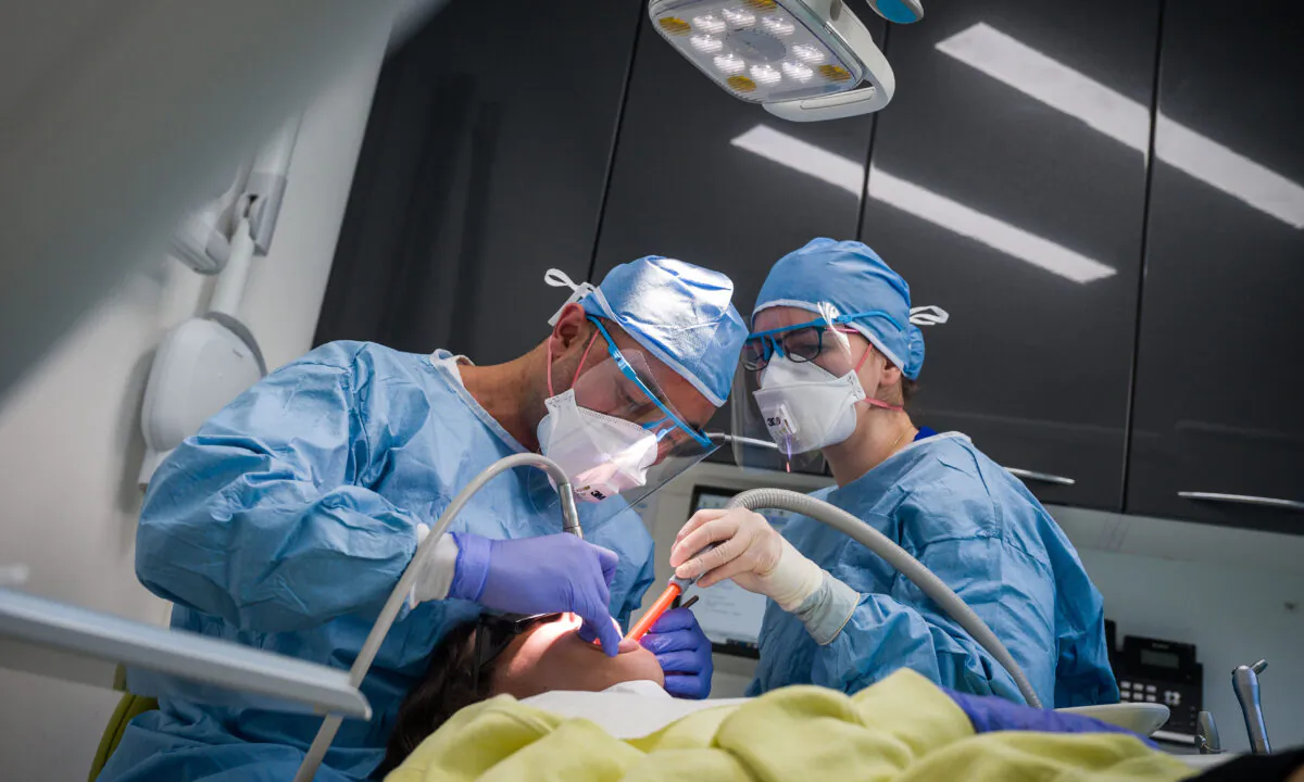 Dentist Fiez Mughal (L) and Dental Nurse Johanna Bartha (R) carry out a procedure on a patient during CCP virus lockdowns at East Village dental practice in London on May 28, 2020. (Leon Neal/Getty Images)