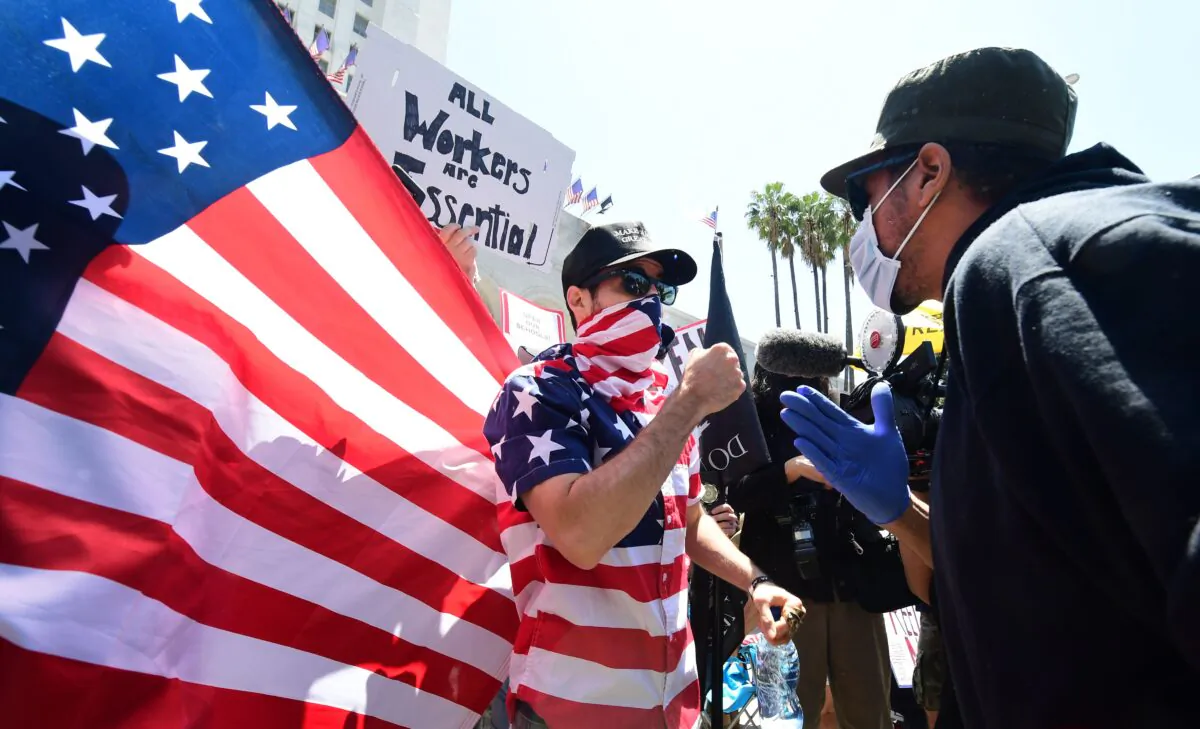A protester (L) argues with a counter-protester (R) in front of the Los Angeles City Hall on May 1, 2020. (Frederic J. Brown/AFP via Getty Images)