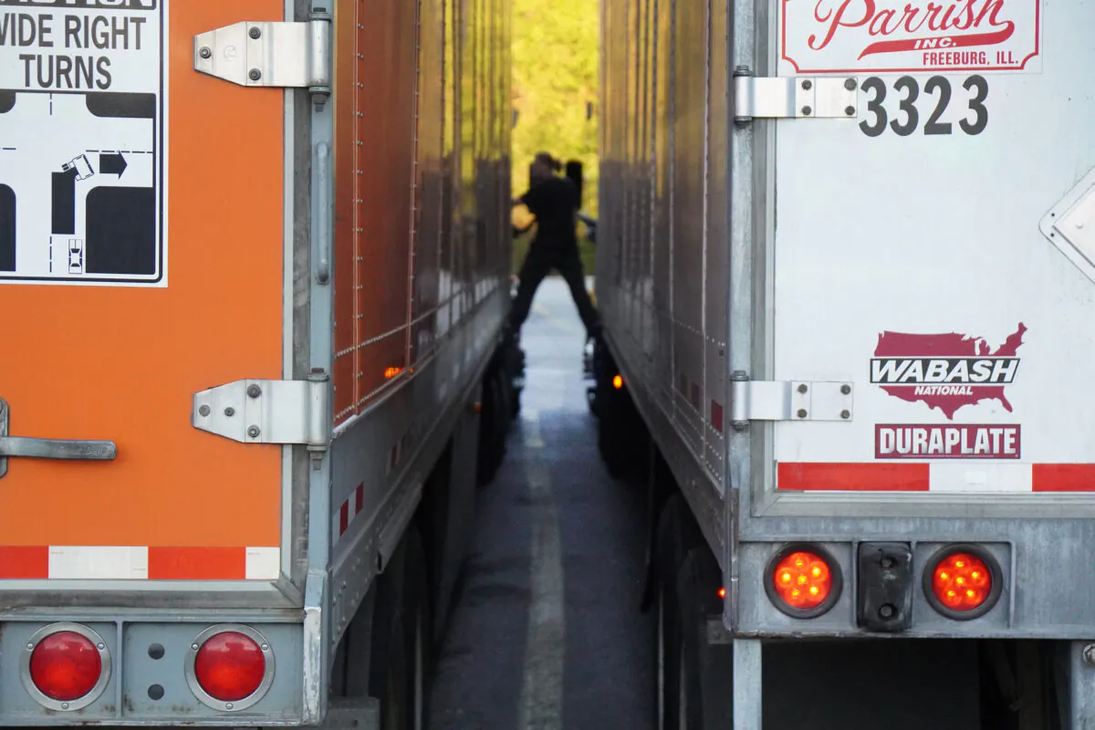 A female trucker stands between rigs while talking at the One9 truckstop in Wildwood, Georgia on Oct. 18, 2021. (Jackson Elliott/The Epoch Times)