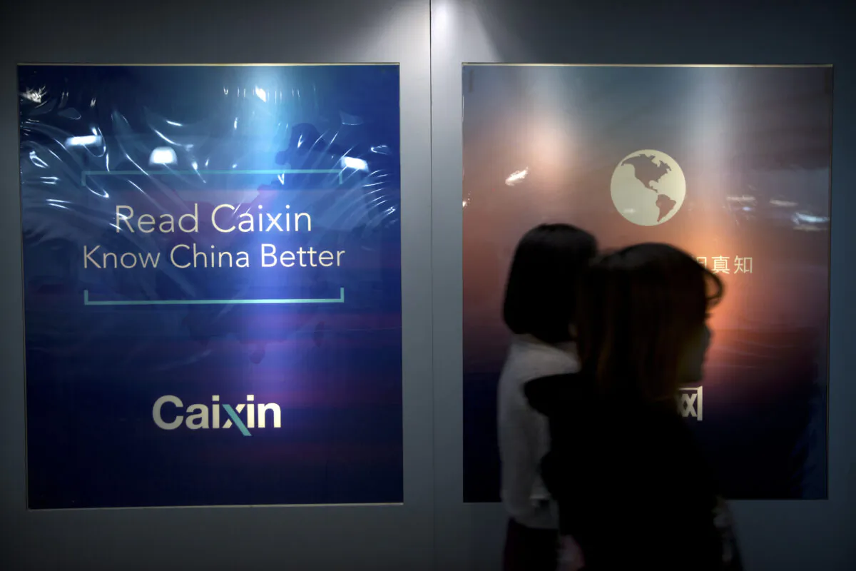 Staffers walk past a billboard at the Caixin Media offices in Beijing on Jan. 18, 2018. (Mark Schiefelbein/AP Photo)