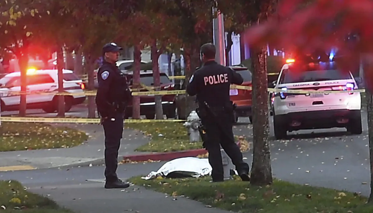 Police stand by a covered body at the scene of a shooting in Tacoma, Wash., on Oct. 21, 2021. (Drew Perine/The News Tribune via AP)
