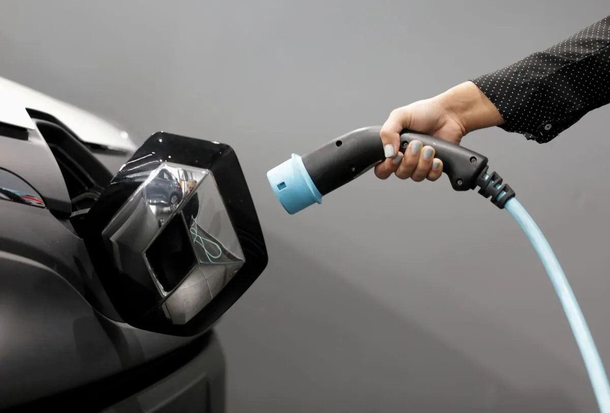A woman holds a cable to charge a Renault Kangoo ZE electric utility vehicle at a Renault dealership in Cagnes-Sur-Mer, France on Oct. 22, 2020. (Eric Gaillard/Reuters)