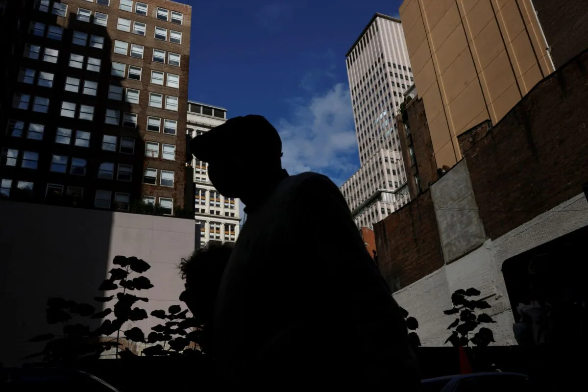 A man is seen silhouetted wearing a protective face mask, amid the coronavirus disease (COVID-19) pandemic, walking near the financial district of New York City on Oct. 18, 2021. (Shannon Stapleton/Reuters)