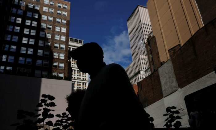 A man is seen silhouetted wearing a protective face mask, amid the coronavirus disease (COVID-19) pandemic, walking near the financial district of New York City on Oct. 18, 2021. (Shannon Stapleton/Reuters)