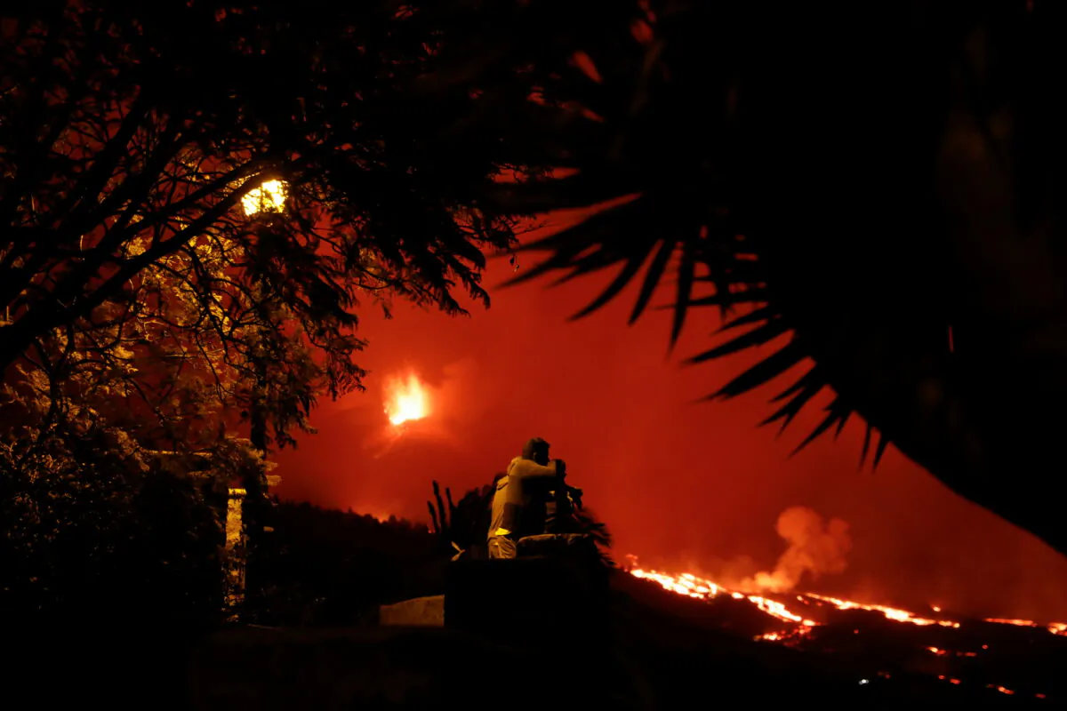 People watch as the Cumbre Vieja volcano continues to erupt on the Canary Island of La Palma, as seen from Tajuya, Spain, on Oct. 23, 2021. (Susana Vera /Reuters)
