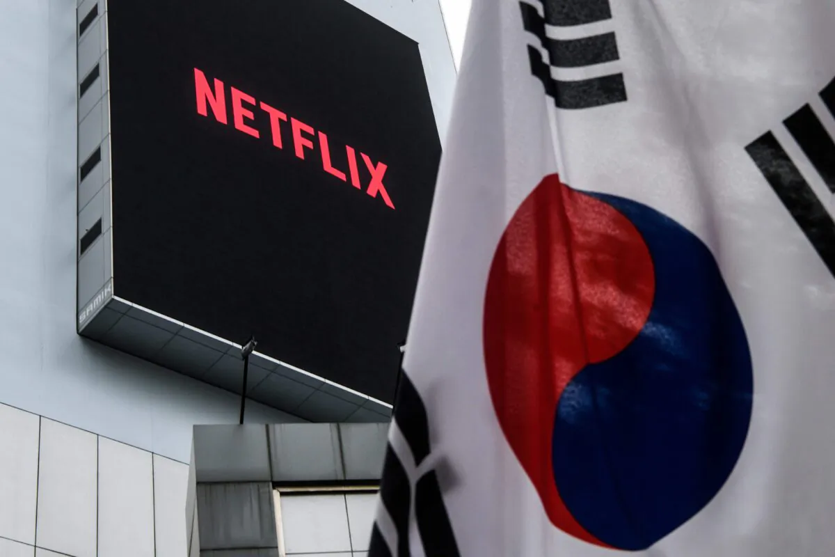 In this photo taken on October 7, 2021, a large digital screen on a building displays the logo of Netflix, producers of the South Korean hit series "Squid Game", beyond a South Korean flag hoisted above a pavement in Seoul. - A dystopian vision of a polarised society, Netflix smash hit Squid Game blends a tight plot, social allegory and uncompromising violence to create the latest South Korean cultural phenomenon to go global.
- TO GO WITH AFP STORY SKOREA-US-TELEVISION-SOCIAL-SQUID GAME,FOCUS BY CLAIRE LEE (Photo by Anthony WALLACE / AFP) / TO GO WITH AFP STORY SKOREA-US-TELEVISION-SOCIAL-SQUID GAME,FOCUS BY CLAIRE LEE (Photo by ANTHONY WALLACE/AFP via Getty Images)