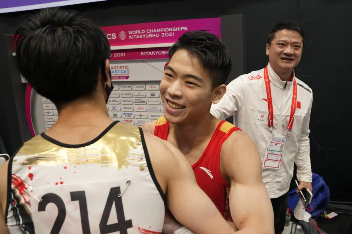 Hu Xuwei (C) of China is congratulated by Kohel Uchimura of Japan after winning the horizontal bar final of the FIG Artistic Gymnastics World Championships in Kitakyushu, western Japan, on Oct. 24, 2021. (Hiro Komae/AP Photo)