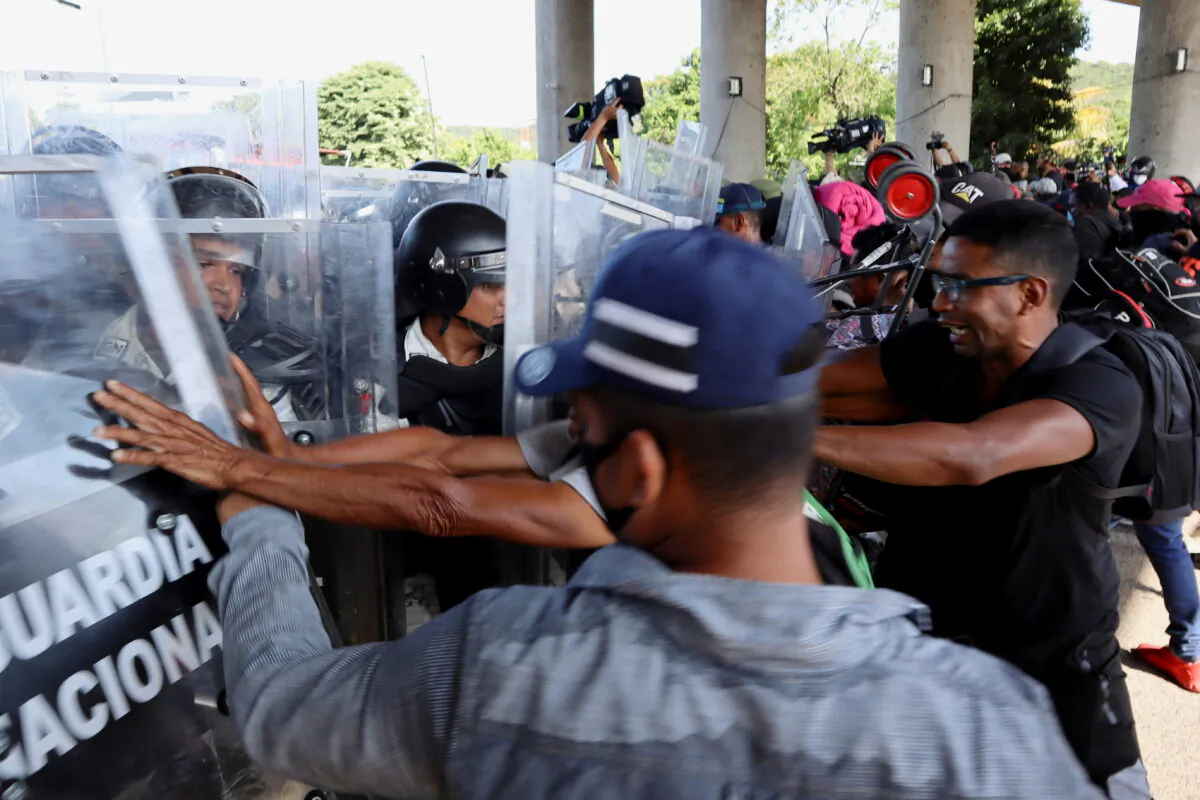 Illegal immigrants from Central America and Haiti clash with National Guard members as they walk in a caravan headed to the Mexican capital to apply for asylum and refugee status, in Tapachula, in Chiapas state, Mexico, on Oct. 23, 2021. (Jose Torres/Reuters)